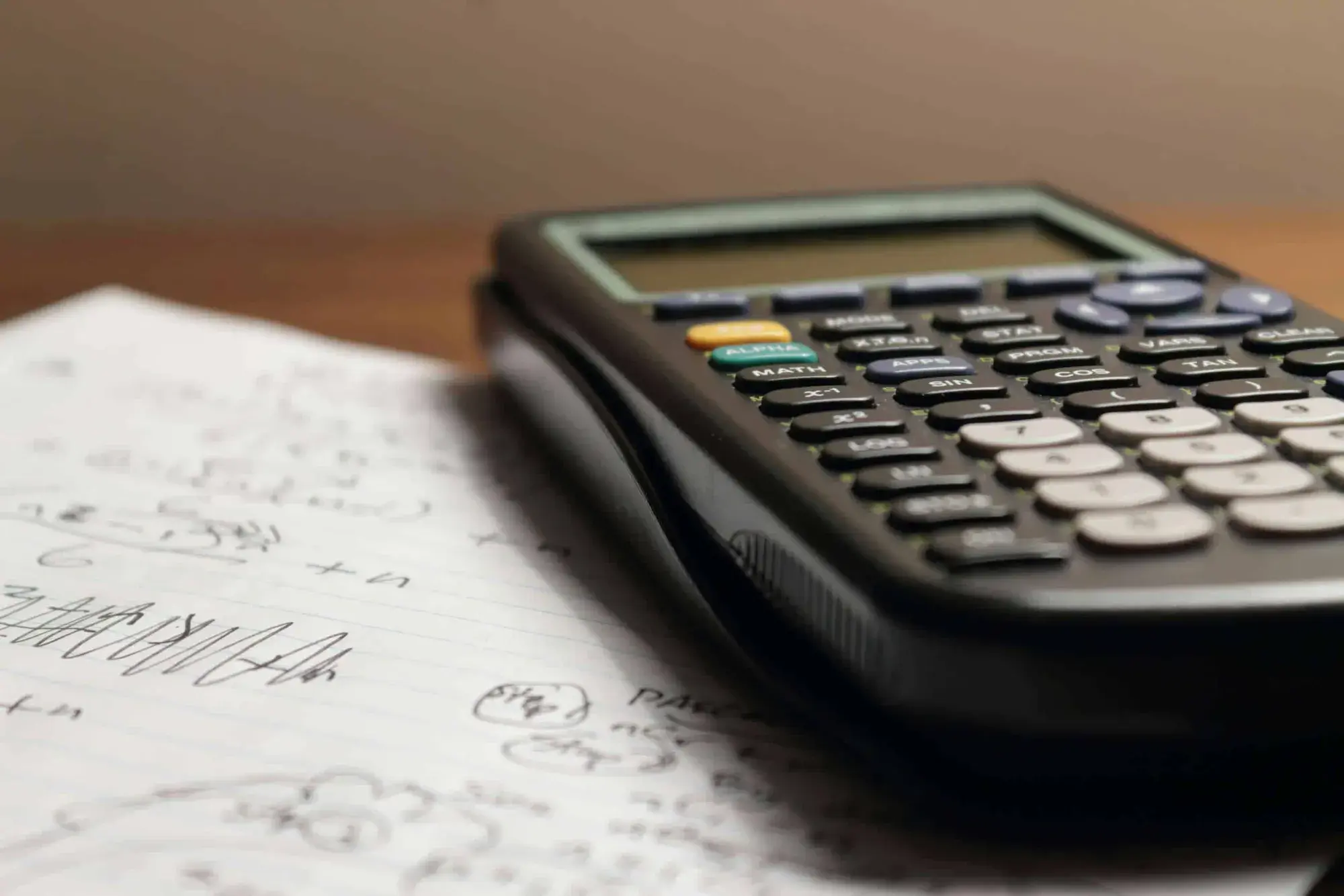 Scientific calculator resting on handwritten maths notes