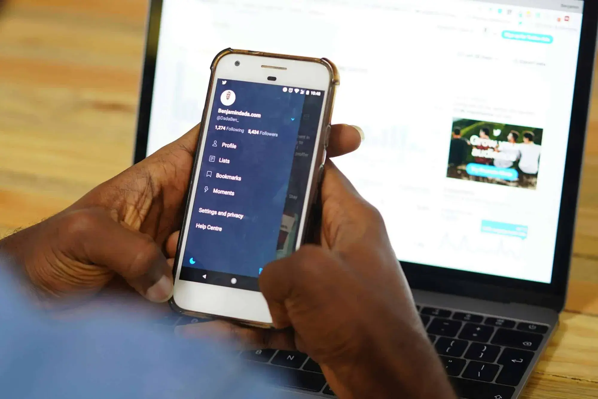 Person using a smartphone in front of a laptop