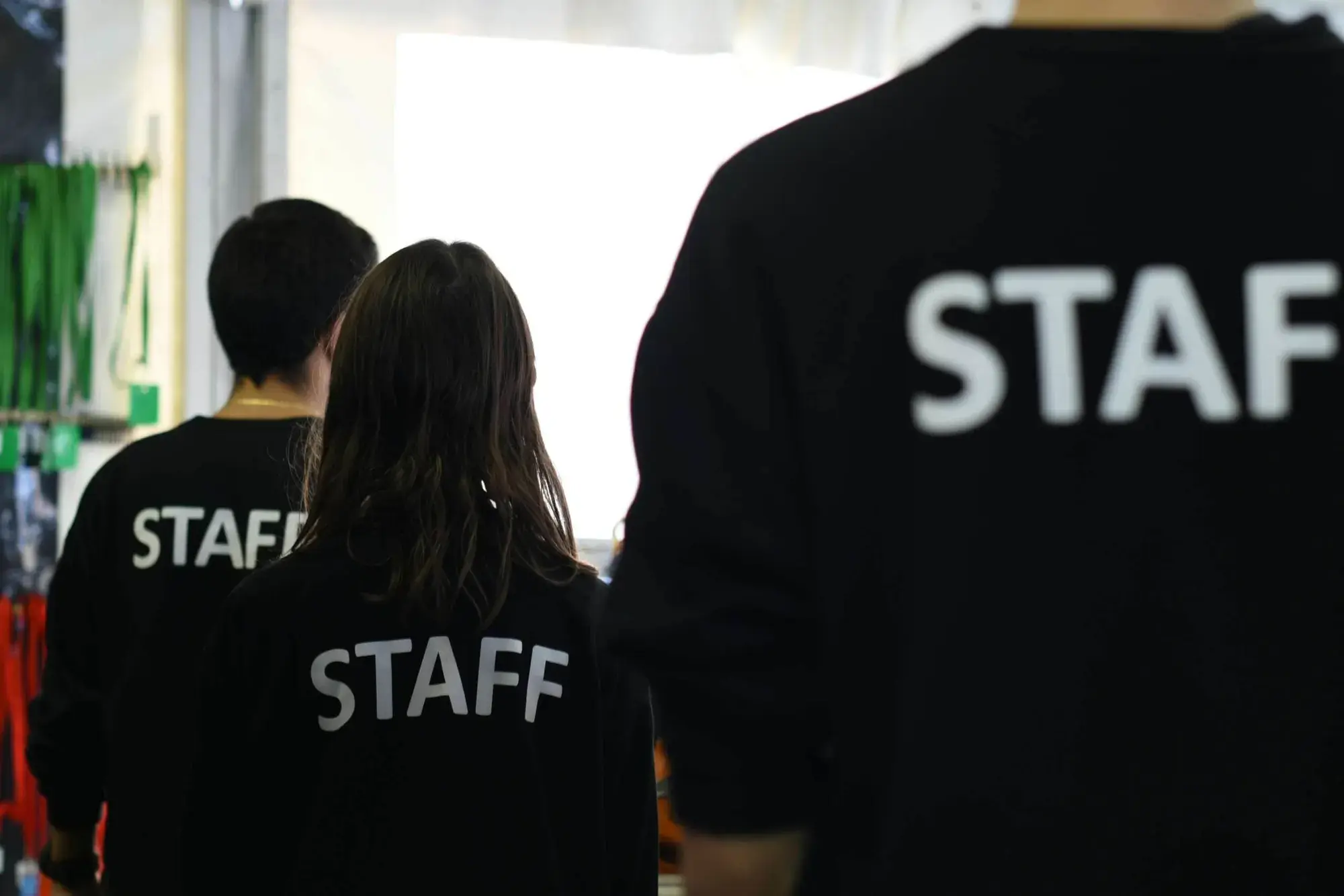 Three staff members in branded STAFF jumpers walking through a workplace, representing a business's employee team